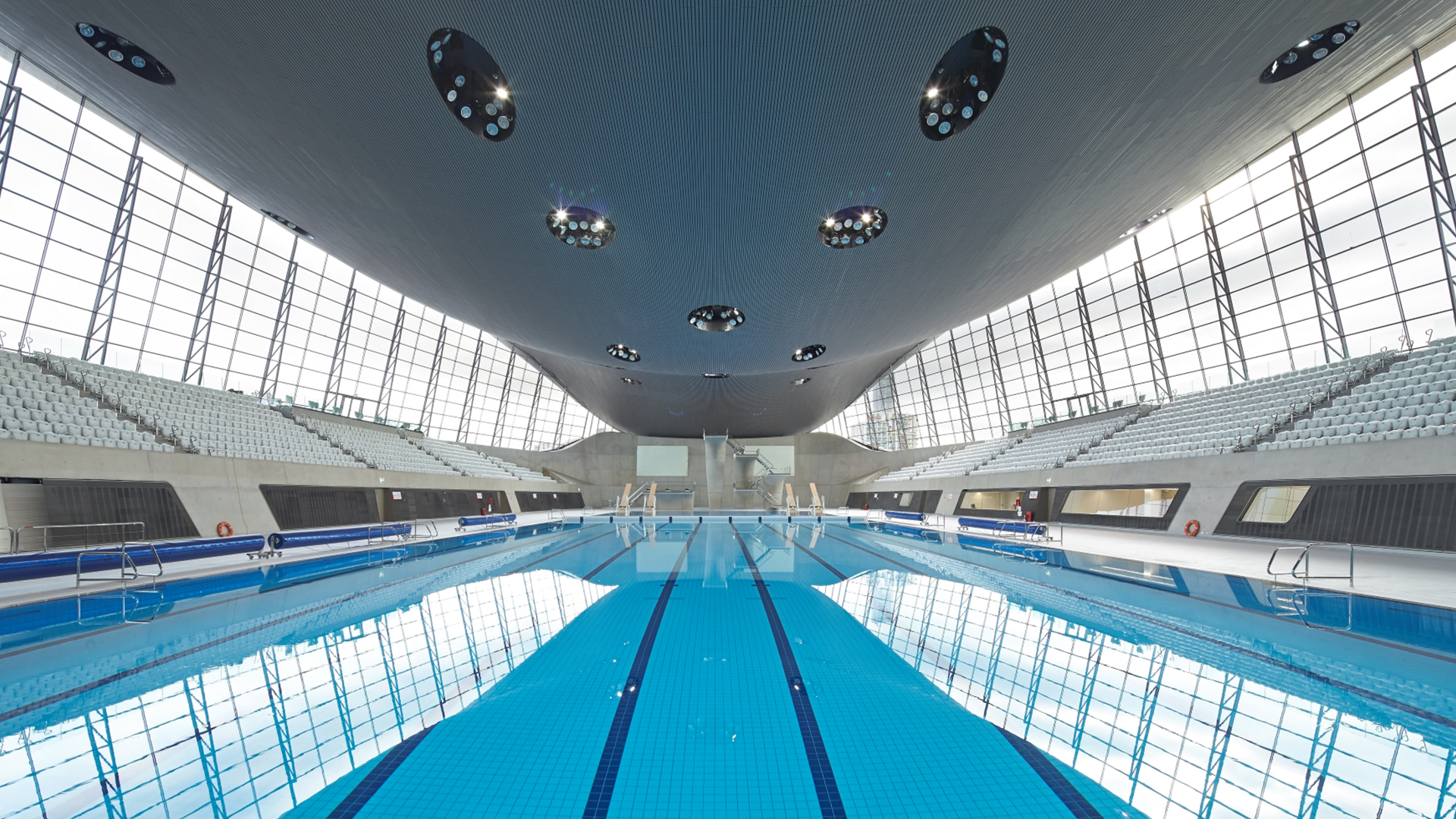 Interior view of the London Aquatics Centre showing the main pool under the iconic wave roof.
